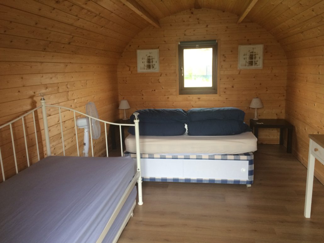 Interior of lakeside pod with bed, sofa bed and dressing table